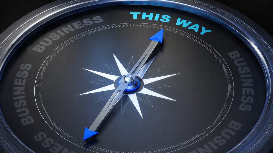 A compass needle pointing to This Way, on a dark business dial